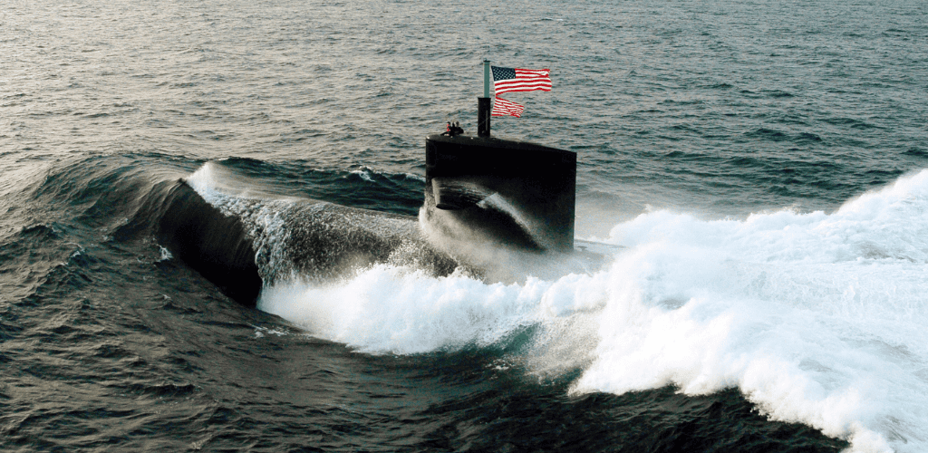 U.s. navy submarine surfacing in the ocean with an american flag waving on the conning tower.